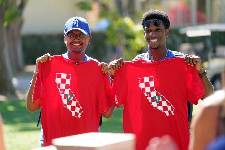 two students holding up shirts